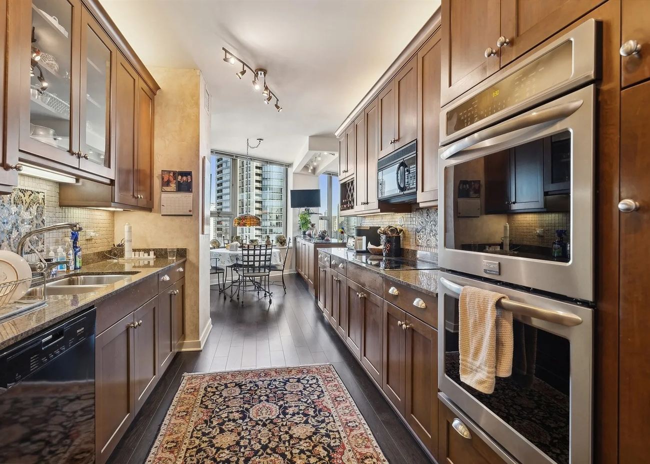 The galley kitchen before renovation: cherry cabinetry, granite counters and a patterned runner