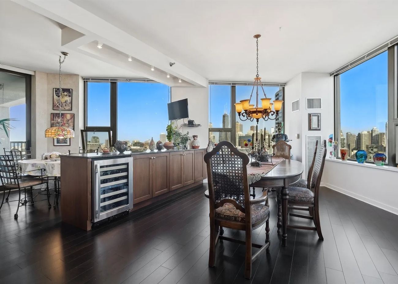 The living and dining room before renovation: dark timber cabinetry, ornate furniture and a brass chandelier