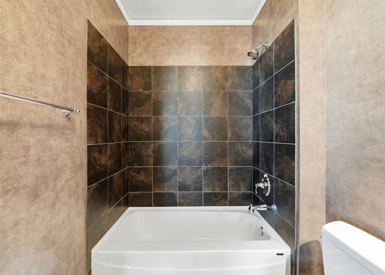 The guest bathroom before renovation: bronze tile surround and a drop-in tub