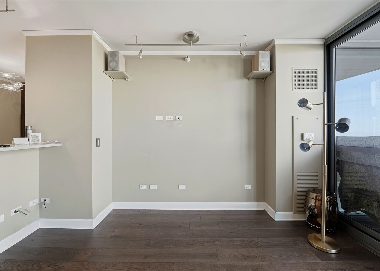 The living room before renovation: bare walls, track lighting and a balcony door